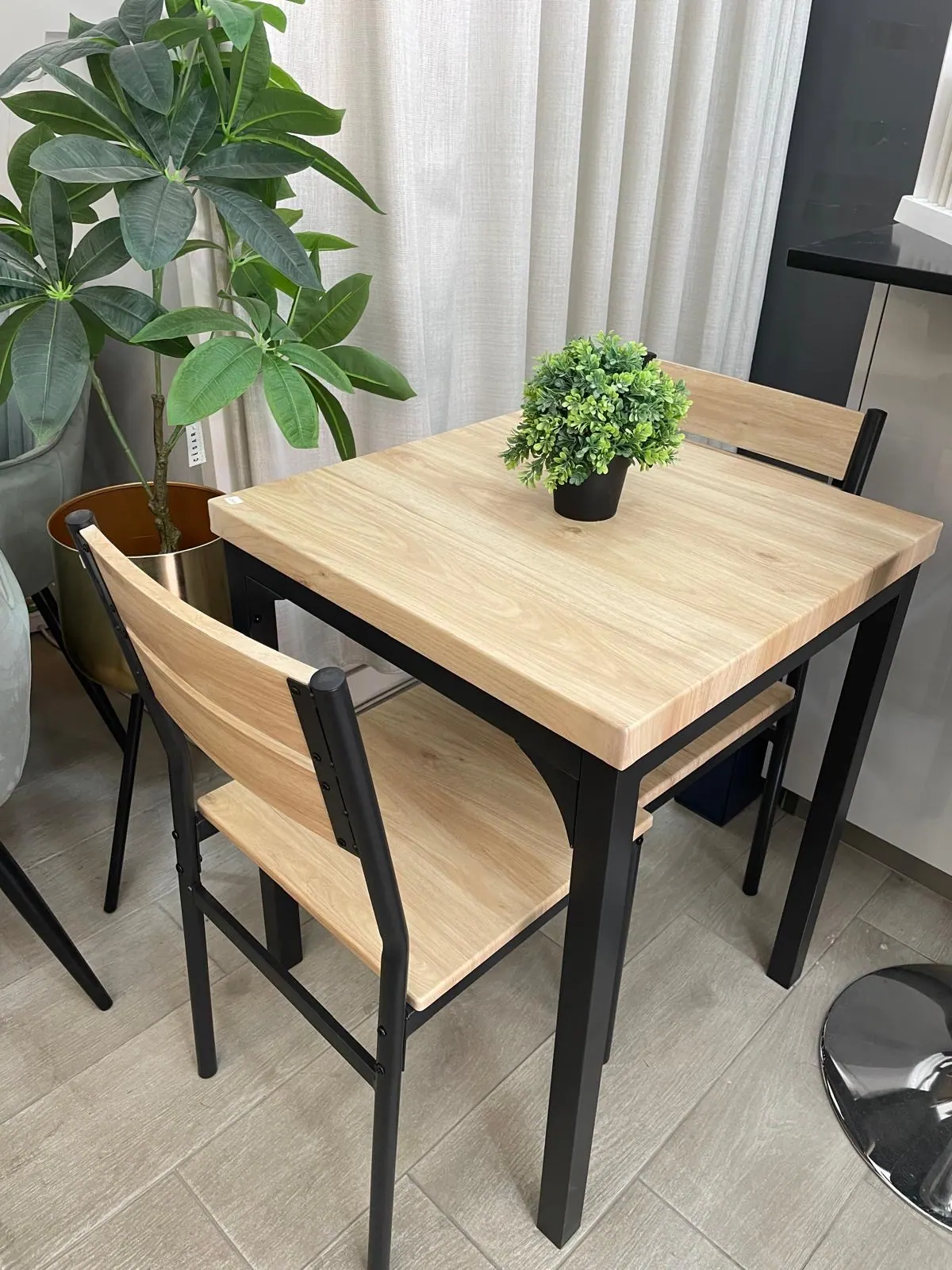 Mesa de jantar em madeira com quatro cadeiras pretas no showroom Henar